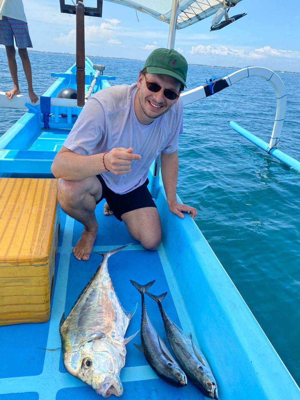 Client proudly holding two big fish on deck