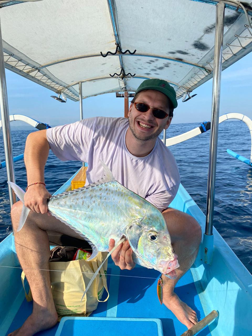 Smiling client with a trevally on the boat