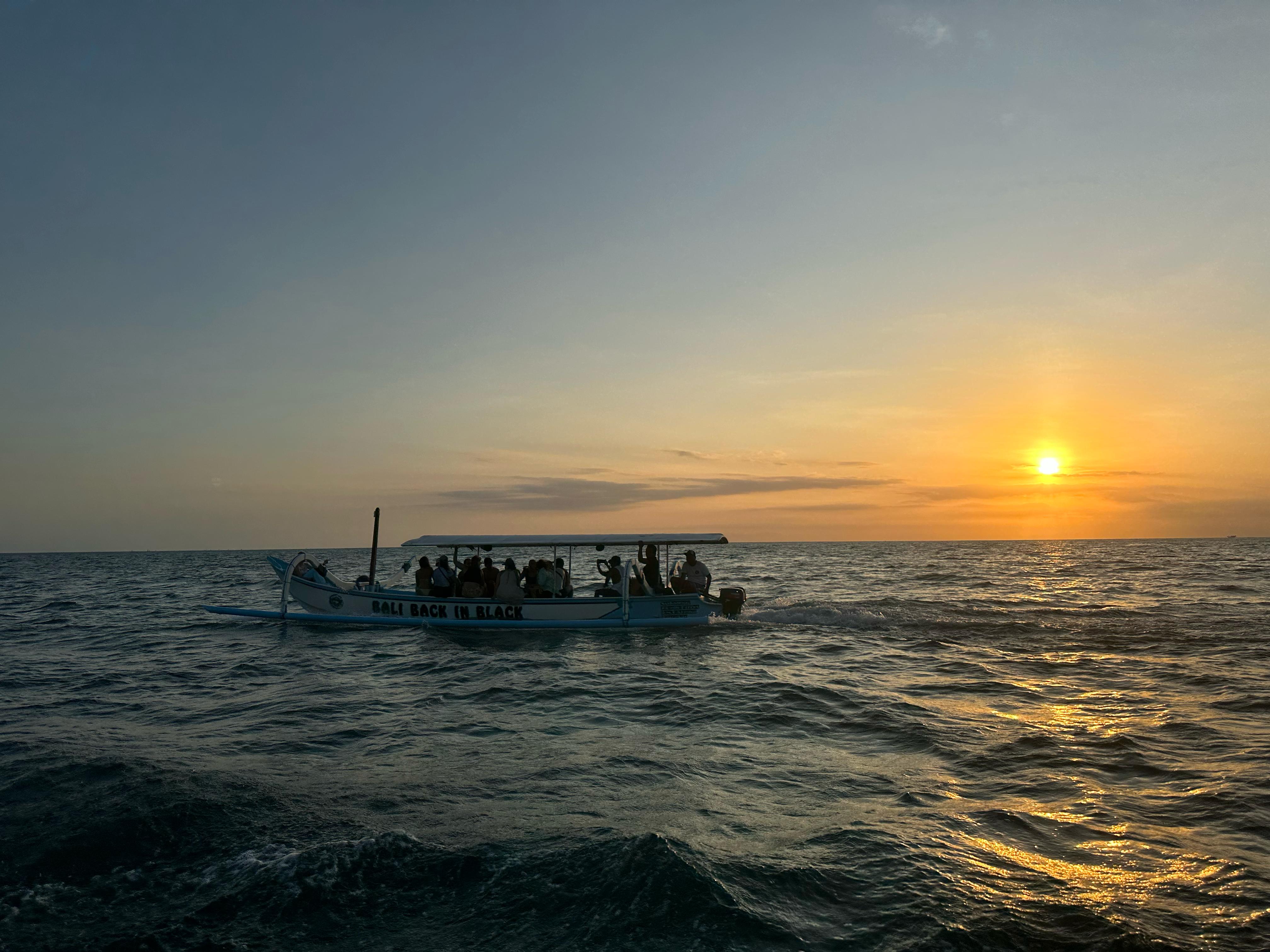 Boat silhouette against golden ocean sunset